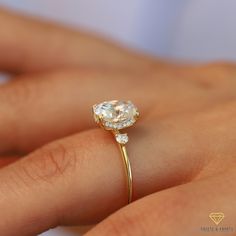 a woman's hand holding a ring with a diamond on the top and side