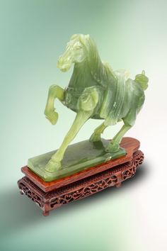 a statue of a horse on a wooden stand with green background and light blue back ground