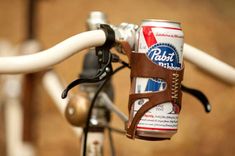 a beer can strapped to the handlebars of a bicycle