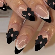 a woman's nails with black bows on them