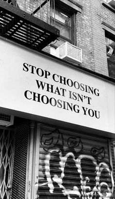 a black and white photo with graffiti on the side of a building that says stop choosing what isn't choosing you