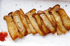 sliced potatoes on a white plate with seasoning sprinkled around the top and bottom