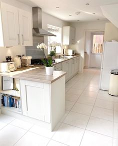 a large kitchen with white cabinets and counter tops is seen in this image from the doorway