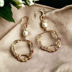 Adorn yourself with elegance using this set of beautiful 18K gold-plated brass flower branch dangly earrings. The charms, delicately crafted, are both intricate and lightweight. The handmade earring hooks, fashioned with 10K gold-filled wire, add a touch of sophistication. At the top, white freshwater pearls with gold-plated floral bead caps enhance the overall charm. Measuring 60mm in length, including the gold-filled wire hooks, this set is a stunning accessory for various occasions. Whether a Gold Feminine Dangle Flower Earrings, Elegant Brass Hoop Earrings With Pearl Drop, Elegant Metal Hoop Flower Earrings, Delicate Gold Hoop Pearl Earrings, Feminine Gold Dangle Pearl Earrings, Feminine Gold Hoop Earrings For Wedding, Elegant 14k Gold-filled Flower Earrings, Elegant 14k Gold Filled Flower Earrings, Elegant Metal Flower Hoop Earrings