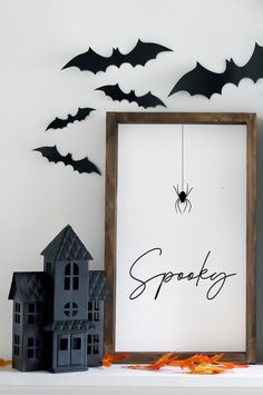 a frame with the word spooky on it next to halloween decorations and bats