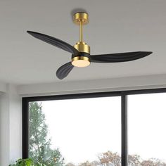 a ceiling fan that is mounted to the ceiling in a living room with large windows