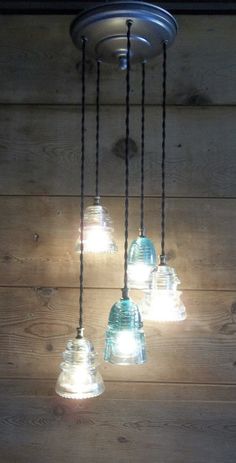 a bunch of lights that are hanging from a ceiling fixture on a wooden wall with wood planks in the background