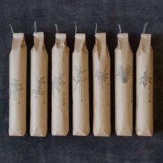 six brown paper bags lined up on top of each other with designs drawn on them