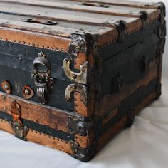 an old trunk is sitting on a white sheet