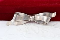 a silver bow tie sitting on top of a red velvet box