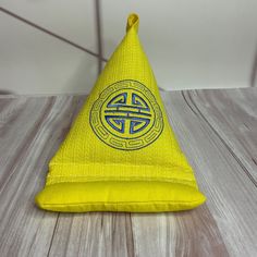 a yellow hat with a blue and white design on the front sitting on a wooden floor