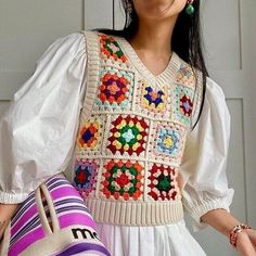 a woman in a white dress holding a colorful purse