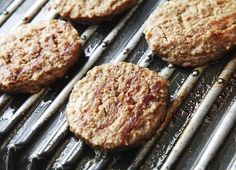 four hamburger patties are cooking on the grill