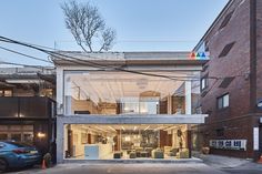 an apartment building with glass walls and lots of windows on the outside, along with a car parked in front of it