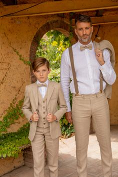 two young boys dressed in tan suits and bow ties, standing next to each other