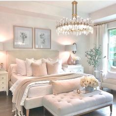 a bedroom with white furniture and chandelier hanging from the ceiling, along with pictures on the wall