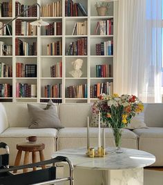 a living room filled with furniture and bookshelves covered in lots of bookcases