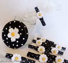 black and white decorated cookies in a jar with polka dots on the top, along with some daisies