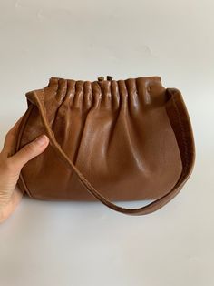 "This is a pretty Kelly style bag made of genuine leather in toffee brown color. This vintage top handle purse is made of soft genuine leather. It has a metal frame and brass kiss lock closure. The interior is lined in polyester fabric. It has one compartment and two slip pockets. This distressed leather Kelly purse will make a wonderful retro statement to your outfit.  Era: 60s 70s Condition: The leather has a distressed look. It has become softer with the wear with some fading around the edges and the closure. The strap shows some fading. The leather has become a shade darker at the top of the handle. There are some dark spots on the lining.  Measurements: Width: 9\"/ 23 cm Heigth: 8.3 \"/ 21 cm Depth: 2\" / 5 cm Strap drop: 6.7\" / 17 cm Color: brown Materials: genuine leather, polyeste Vintage Brown Bags With Hasp Closure, Retro Brown Bag With Snap Closure, Vintage Brown Bag With Hasp Closure, Vintage Cognac Bag With Gold-tone Hardware, Black Waist Belt, Vintage Brown Bag With Gold-tone Hardware, Kelly Bag, Leather Conditioner, Distressed Leather