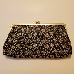 Classy Vintage 1960s Clutch Bag Made Of Black Satin With Raised Gold Brocade Floral Design. Gold Tone Metal Hinged Frame And Kiss Lock Closure. Lined With Gold Satin Acetate. Excellent Never Used Condition. Measures 8.5 In Wide By 5 In. Retro Black Bags For Vintage Events, Retro Vintage Black Evening Bag, Retro Black Evening Bag, Retro Clutch For Evening Use, Retro Clutch Evening Bag For Everyday Use, Retro Pouch Bag For Party, Retro Party Pouch Bag, Vintage Black Rectangular Coin Purse, Vintage Black Pouch Evening Bag