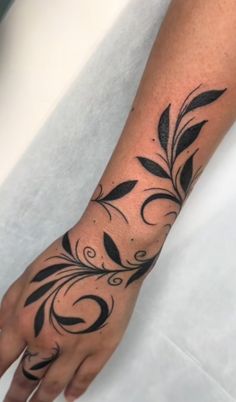 a woman's hand with black ink on it and an artistic flower tattoo design