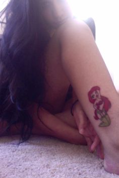 a woman laying on the floor with her arm and foot covered by a mario tattoo