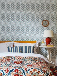 a bed in a bedroom with blue and white wallpaper, two nightstands and a lamp