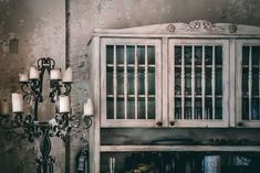 an old fashioned china cabinet with glass doors and chandelier in a kitchen area