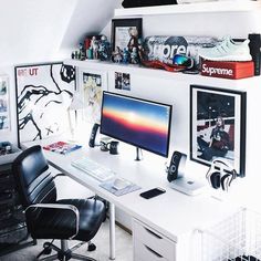 a white desk topped with a computer monitor next to a black chair and other items