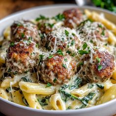 a white bowl filled with pasta and meatballs covered in parmesan sprinkles