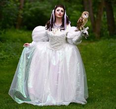 a woman in a white dress holding an owl