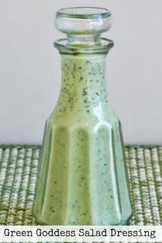 a small glass bottle sitting on top of a green tableclothed place mat with a white wall in the background