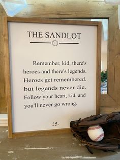 a baseball mitt sitting next to a sign that says, the sandlot remembers kid, there's hero and there's legend