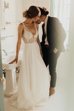 a bride and groom kissing in the bathroom