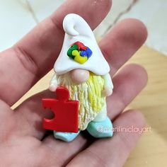 a small toy gnome holding a red letter