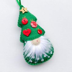 a green christmas ornament hanging on a white wall with red buttons and fur