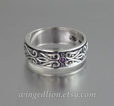 The lavishly ornamented PRINCE CHARMING wedding band was inspired by Renaissance art. PRINCE CHARMING band will be made to order in sterling silver in the size specified by the customer. The band is 7.5mm wide and adorned with intricate carvings. It will be oxidized to add contrast to the beautiful scrollwork. The ring is decorated with a 2mm natural purple Amethyst. Other gemstone options are available. Designed and crafted by Sergey Zhiboedov. © SZ Jewelry Design For the current turnaround time check our shop announcement or contact us. Please check out our "Shop Policies" at www.etsy.com/shop/WingedLion/policy for information regarding payment plans, warranties, etc. International customers are responsible for any import duties or taxes charged by the recipient's country. Silver Amethyst Ring With Intricate Design For Wedding, Engraved Silver Amethyst Ring In Sterling Silver, Engraved Sterling Silver Amethyst Ring For Anniversary, Spiritual Sterling Silver Amethyst Wedding Ring, Spiritual Sterling Silver Amethyst Ring For Wedding, Elegant Engraved Silver Amethyst Ring, Elegant Silver Engraved Amethyst Ring, Silver Amethyst Ring With Intricate Design For Anniversary, Charming Wedding