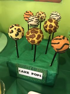 cake pops with animal print on them sitting on a green tablecloth in front of a mirror