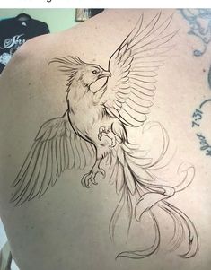 the back of a woman's shoulder with a bird tattoo on it