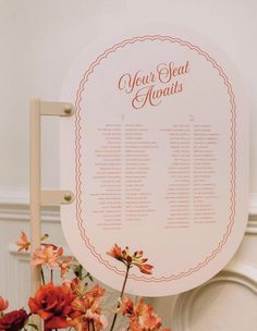 a sign that says your seat awaits with flowers in the foreground and on the back