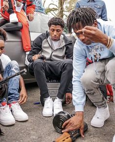 a group of young men sitting next to each other on top of a street corner