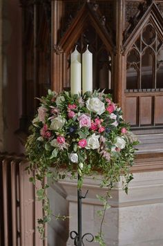 a floral centerpiece with candles in the background