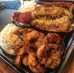 a tray with shrimp, mashed potatoes and other food items on top of it