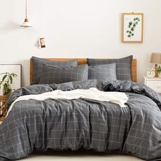 a bed with grey plaid sheets and pillows