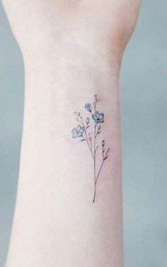 a small blue flower tattoo on the left side of the wrist is shown in this image