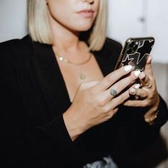 a woman holding a cell phone in her right hand and looking at the screen with both hands