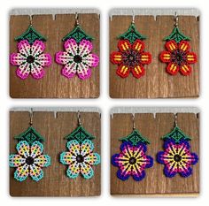 four different designs of beaded earrings hanging from hooks on a wooden surface, each with an individual's own flower ornament