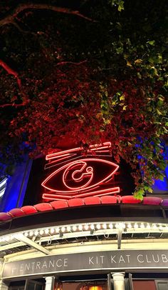 an illuminated sign on the side of a building with red and blue lights around it