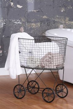 a dog sitting in a basket on top of a wooden floor next to a bath tub