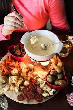 a woman sitting at a table filled with food and dipping sauce on top of it